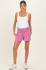 woman wearing a white tank top and pink maternity shorts with pockets, showing a baby bump