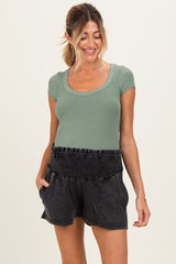 woman wearing a dark gray smocked waistband maternity short and a fitted green ribbed top