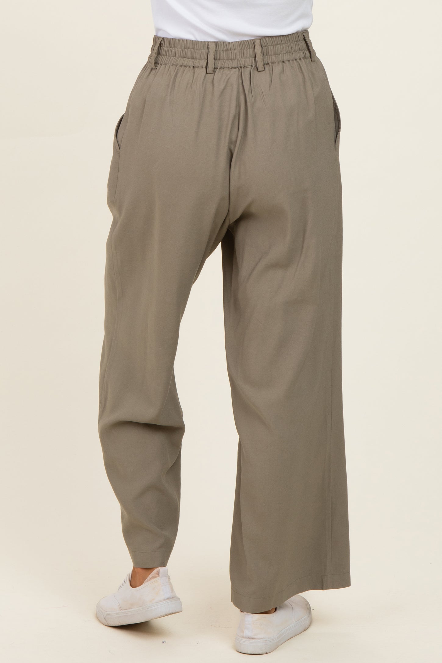 woman wearing beige wide-leg trousers with an elastic waistband and side pockets, viewed from the back