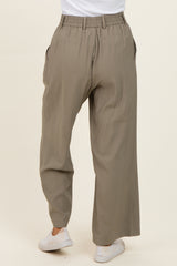woman wearing beige wide-leg trousers with an elastic waistband and side pockets, viewed from the back
