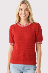 woman wearing a red textured knit sweater with short puff sleeves and striped neckline, smiling at the camera
