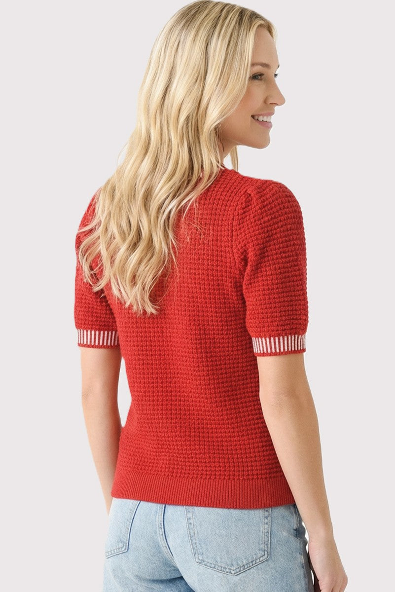 woman wearing a red textured short sleeve sweater with striped cuffs and a relaxed fit, seen from the back