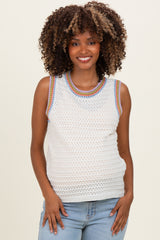 woman wearing a white sleeveless crochet maternity top with colorful trim and displaying her baby bump