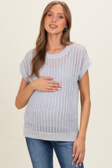 woman wearing a light gray maternity top with a textured design and holding her baby bump