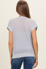woman wearing a light gray maternity top with a sheer, striped back and rolled short sleeves