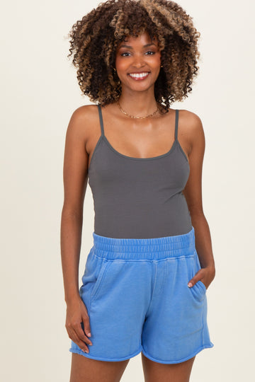 woman wearing a gray maternity tank top and blue maternity shorts with pockets, smiling at the camera