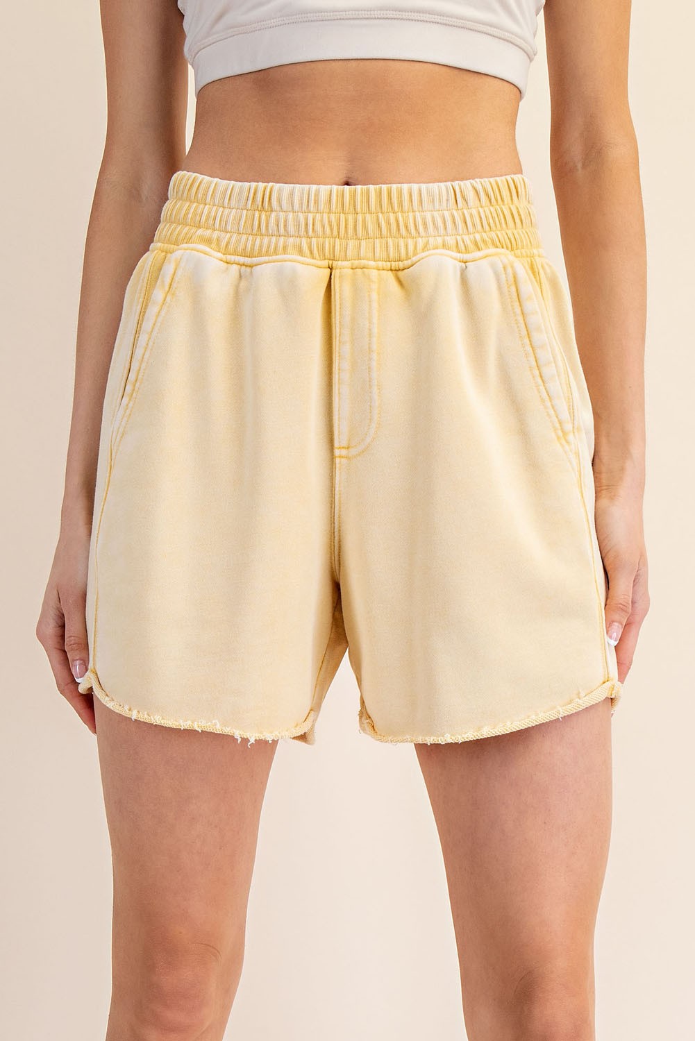 woman wearing yellow distressed high-waisted shorts with an elastic waistband and side pockets