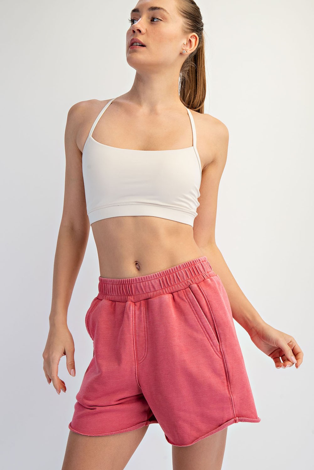 woman wearing a white crop top and pink sweat shorts with an elastic waistband