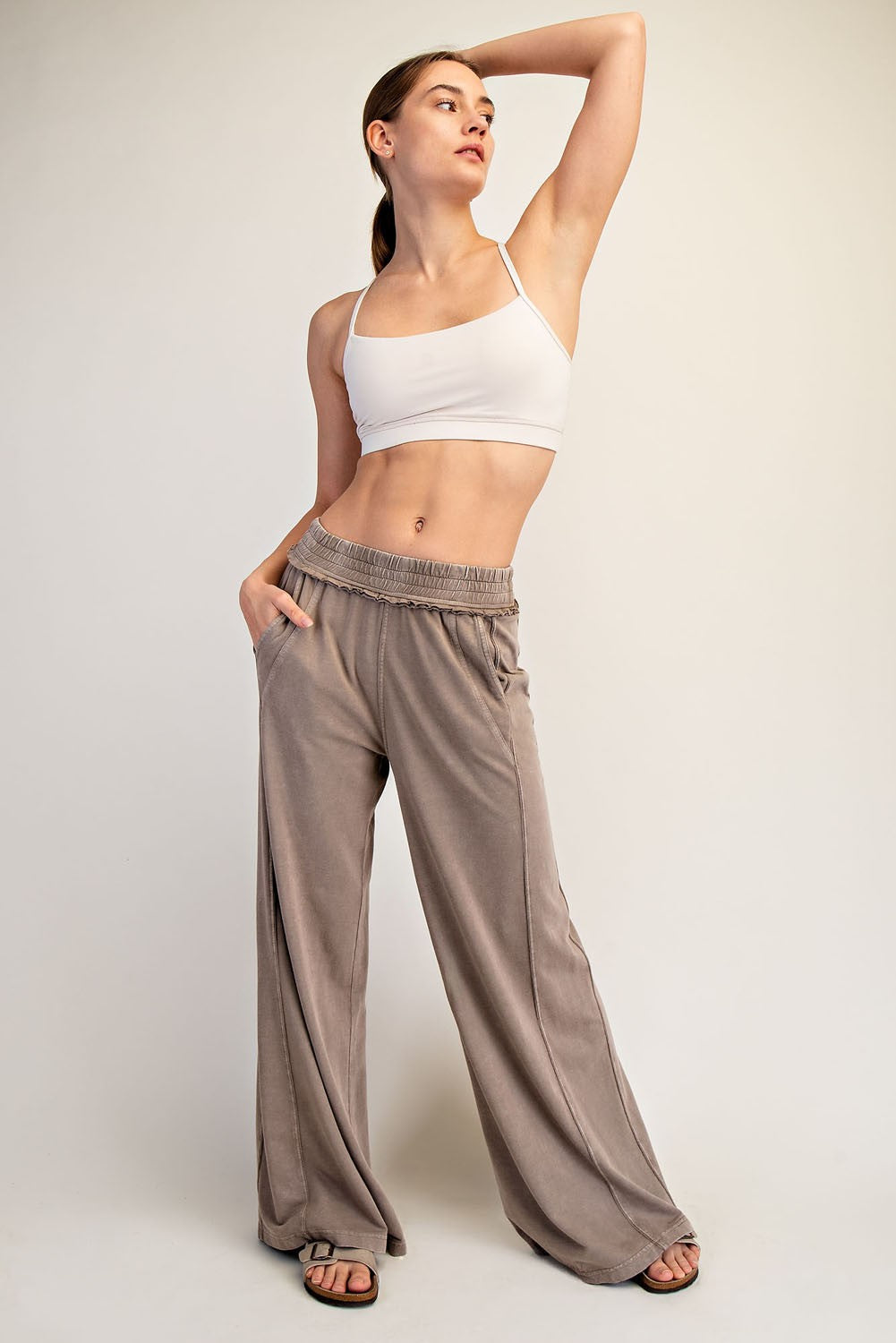 woman wearing a cream cropped tank top and taupe wide-leg pants with pockets, posed elegantly