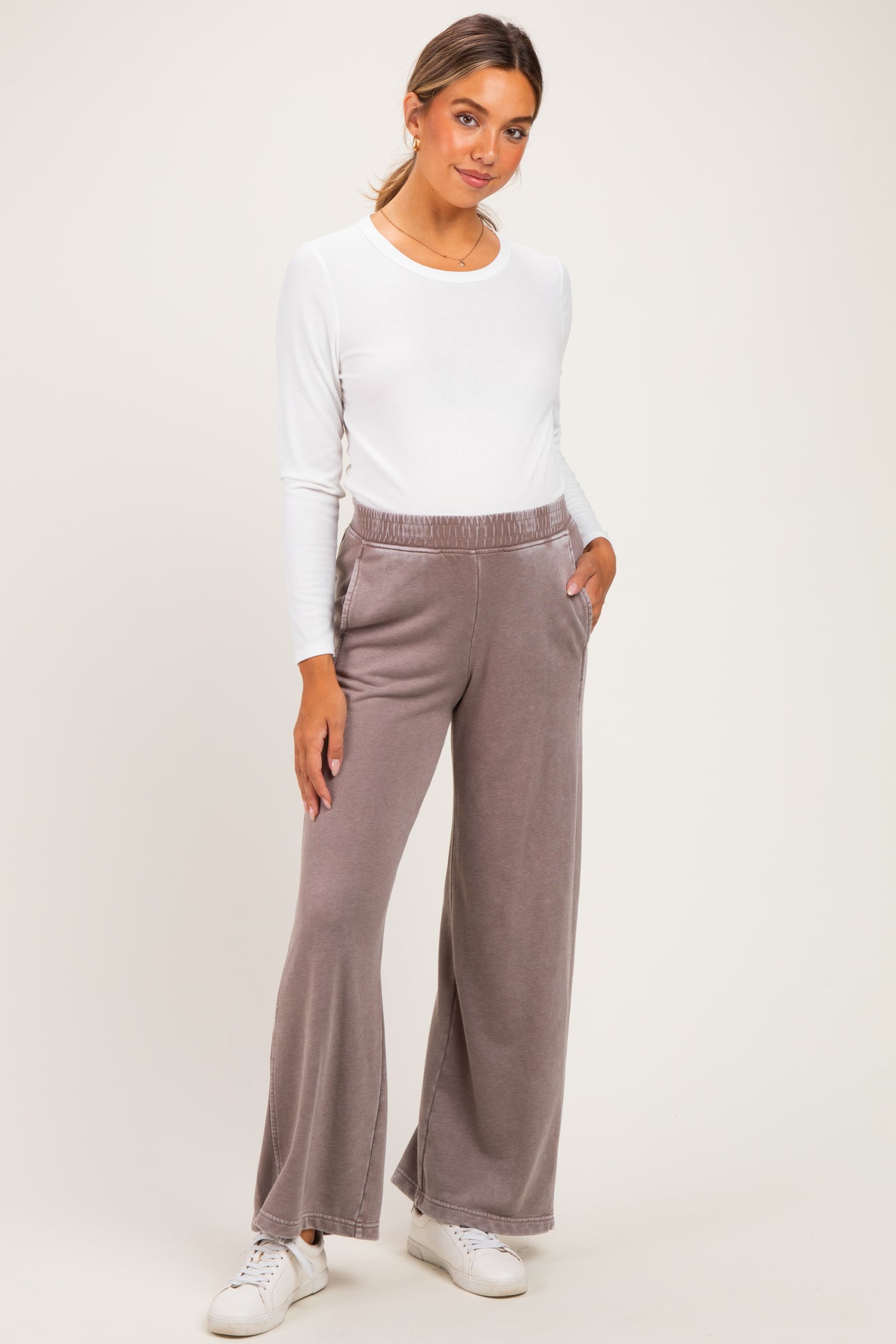 woman wearing a white long sleeve maternity top and gray wide-leg maternity pants with pockets