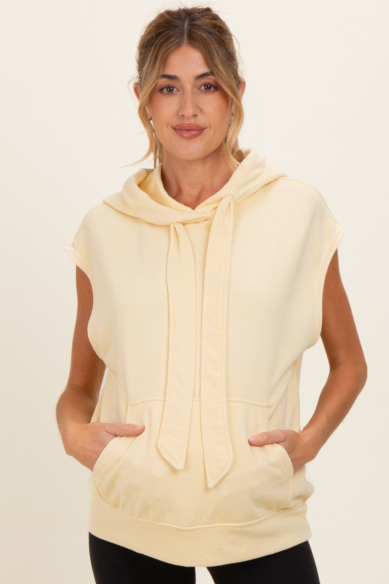 woman wearing a light yellow maternity hoodie with a relaxed fit and kangaroo pocket