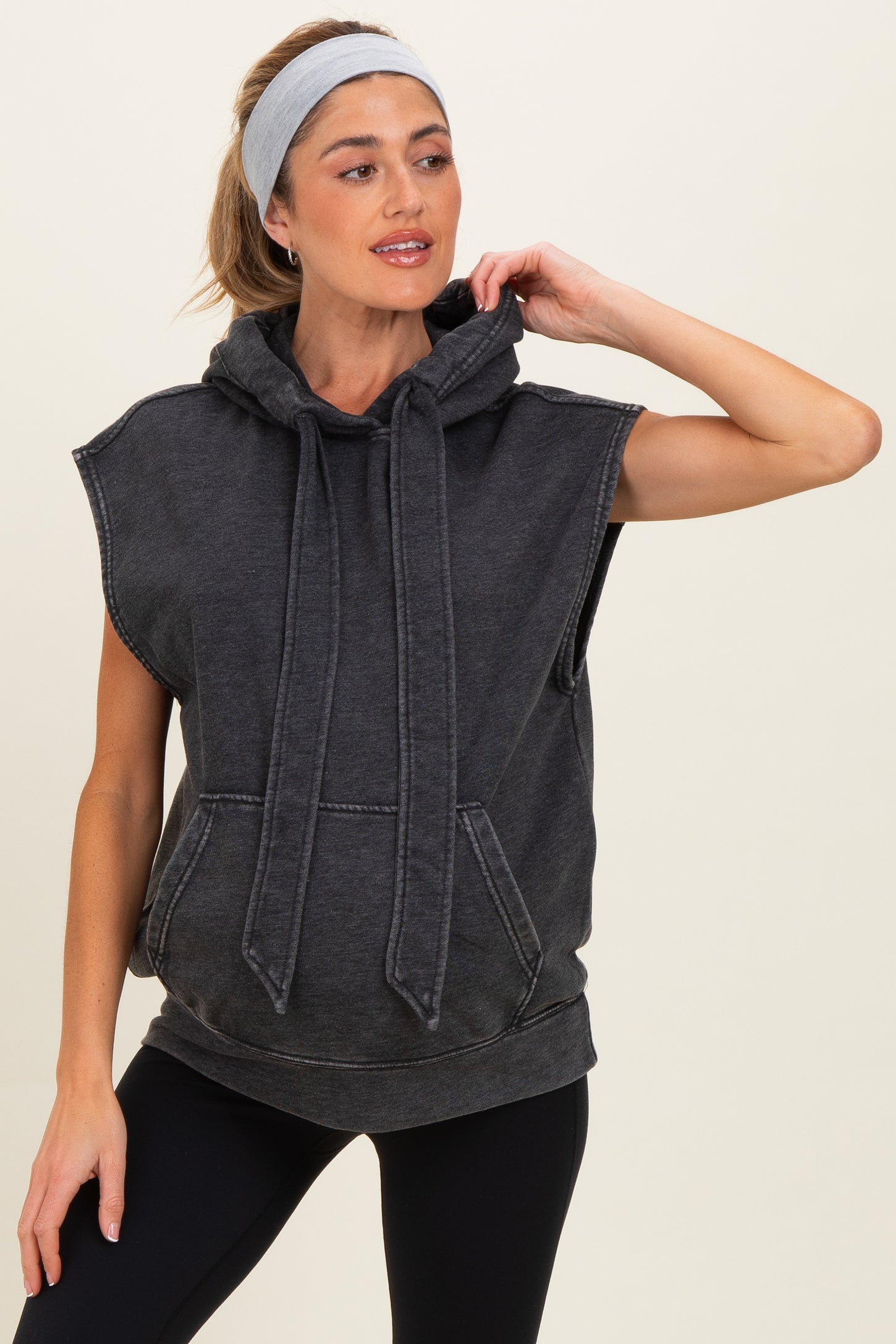 woman wearing a dark gray sleeveless maternity hoodie with a front pocket and drawstring hood