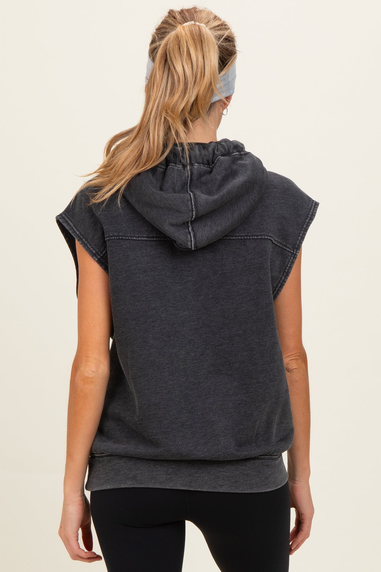 woman wearing a dark gray maternity hooded sweatshirt with short sleeves and a relaxed fit, showing the back view
