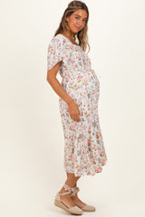 woman wearing a floral print maternity dress with a tie waist and ruffled hem, showing her baby bump