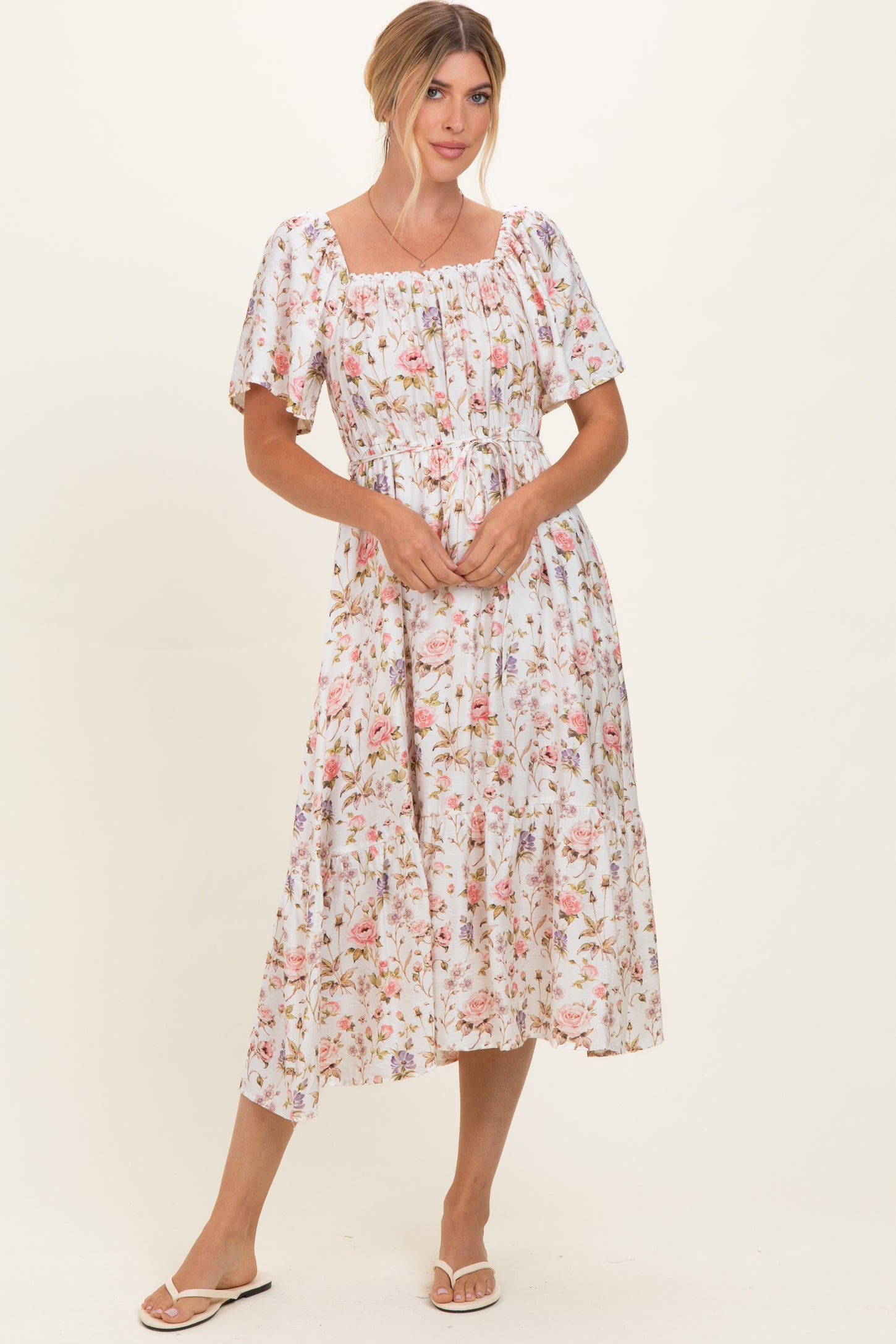 woman wearing a floral midi dress with puff sleeves and a smocked bodice, standing against a plain background