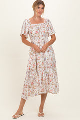 woman wearing a floral midi dress with puff sleeves and a smocked bodice, standing against a plain background