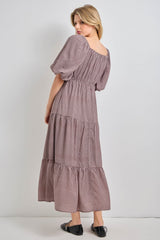 woman wearing a brown and white checkered maxi dress with puff sleeves and tiered skirt, shown from the back