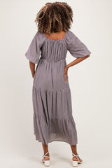 woman wearing a black and white gingham maternity maxi dress with flutter sleeves and a tiered skirt