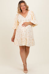 woman wearing a cream floral maternity dress with puff sleeves and a ruffled hem, gently cradling her baby bump