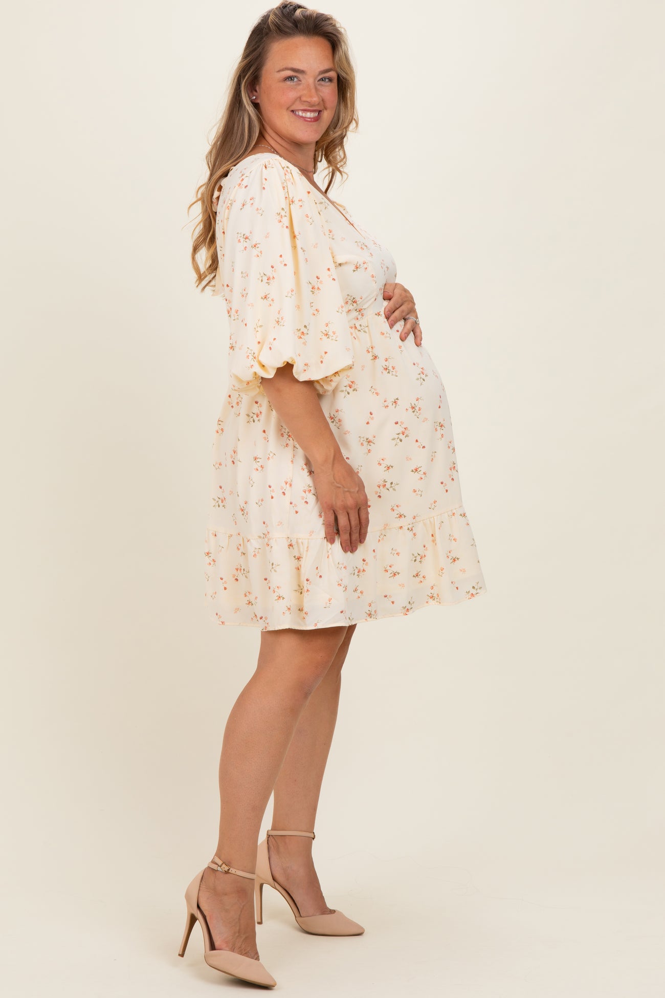 woman wearing a floral short sleeve maternity dress and holding her baby bump