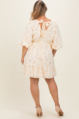 woman wearing a cream floral print maternity dress with puff sleeves and a back tie detail