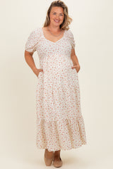 woman wearing a floral maternity plus maxi dress with short puff sleeves and side pockets, displaying a baby bump