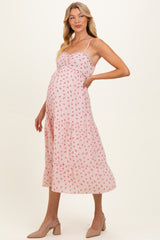 woman wearing a pink floral maternity dress with a tiered skirt and adjustable straps, highlighting her baby bump