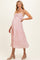 woman wearing a pink floral maternity dress with a tiered skirt and adjustable straps, highlighting her baby bump
