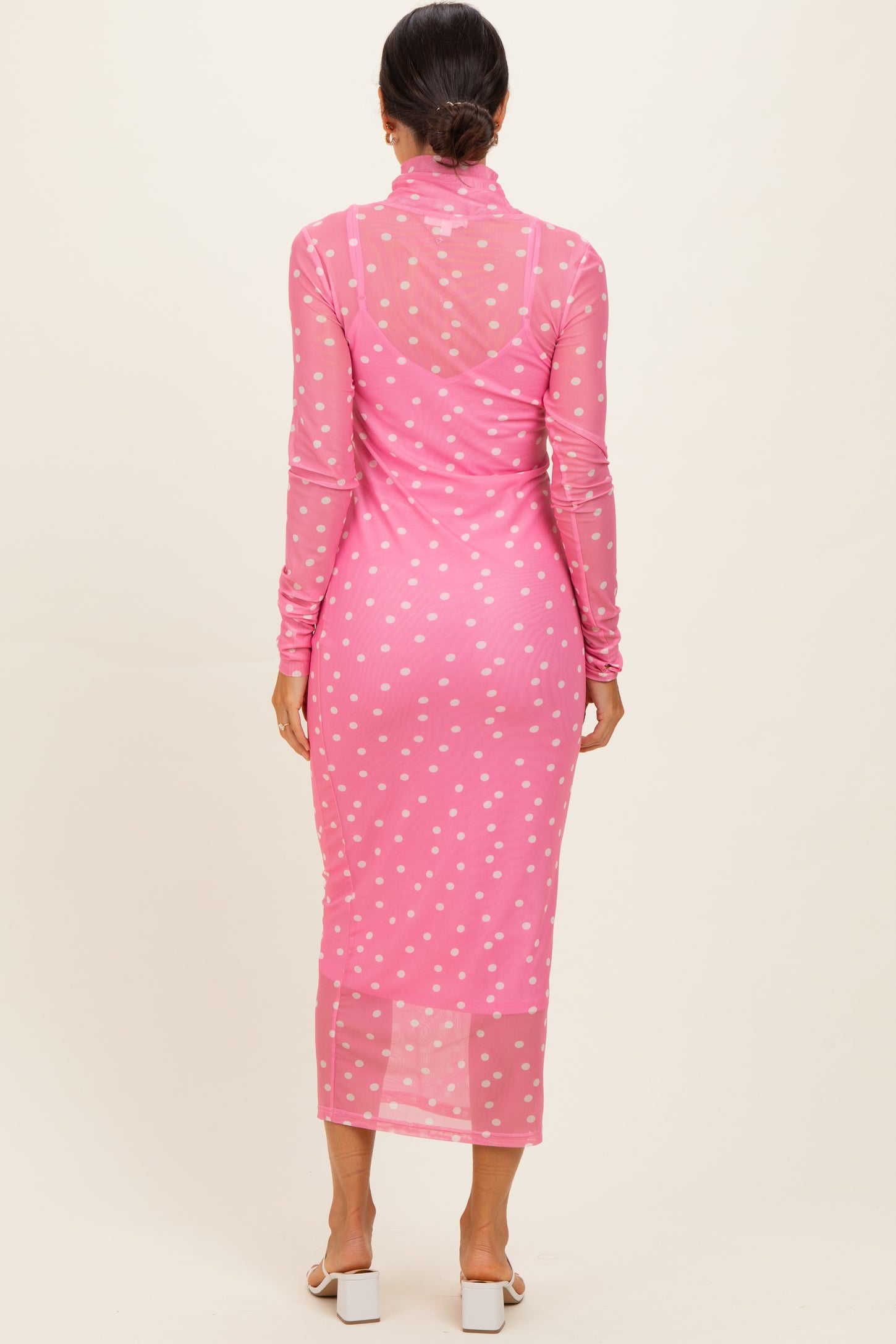 woman wearing a pink long sleeve polka dot mesh dress with a form-fitting silhouette and a midi length