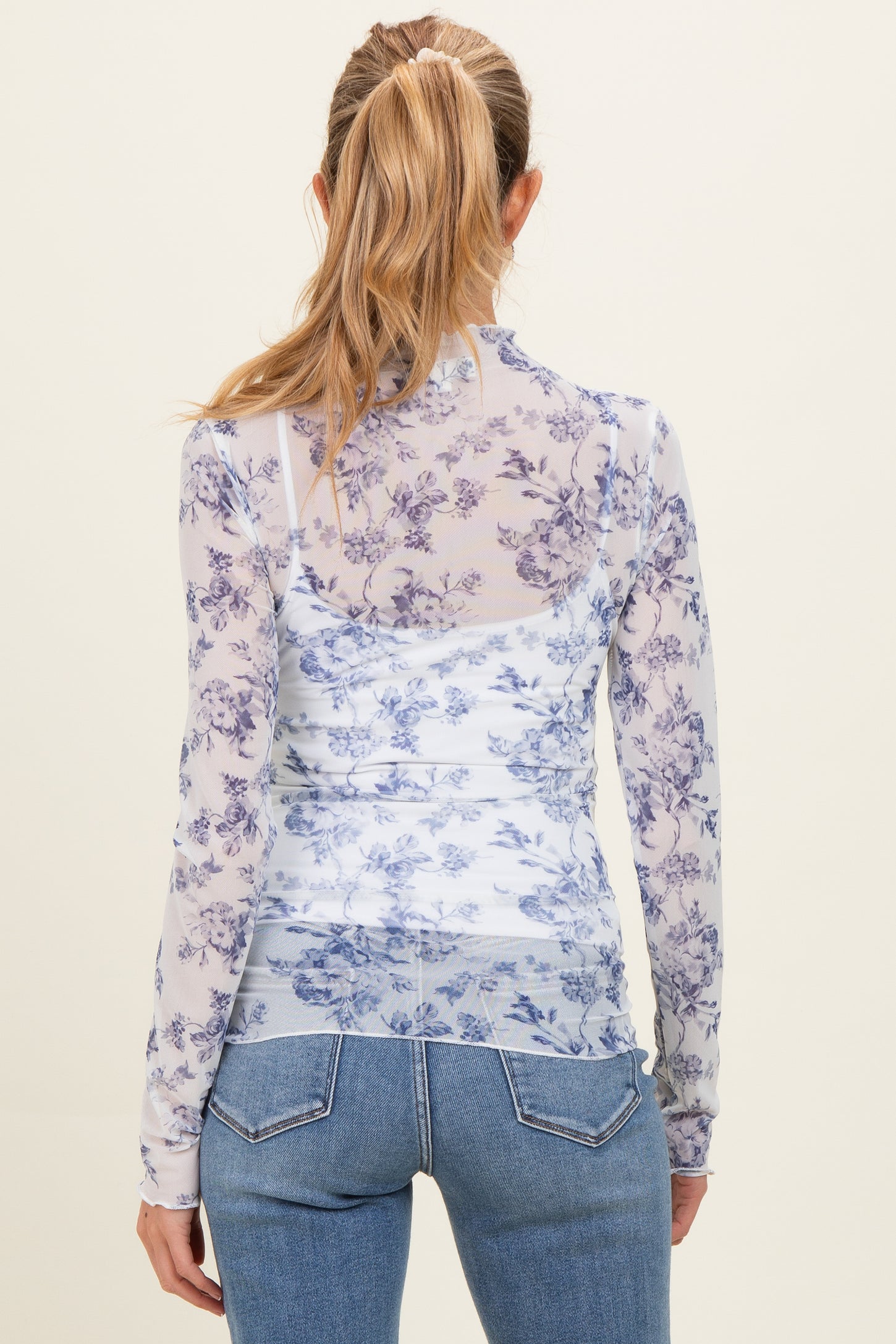 woman wearing a sheer purple floral long sleeve maternity top, viewed from the back