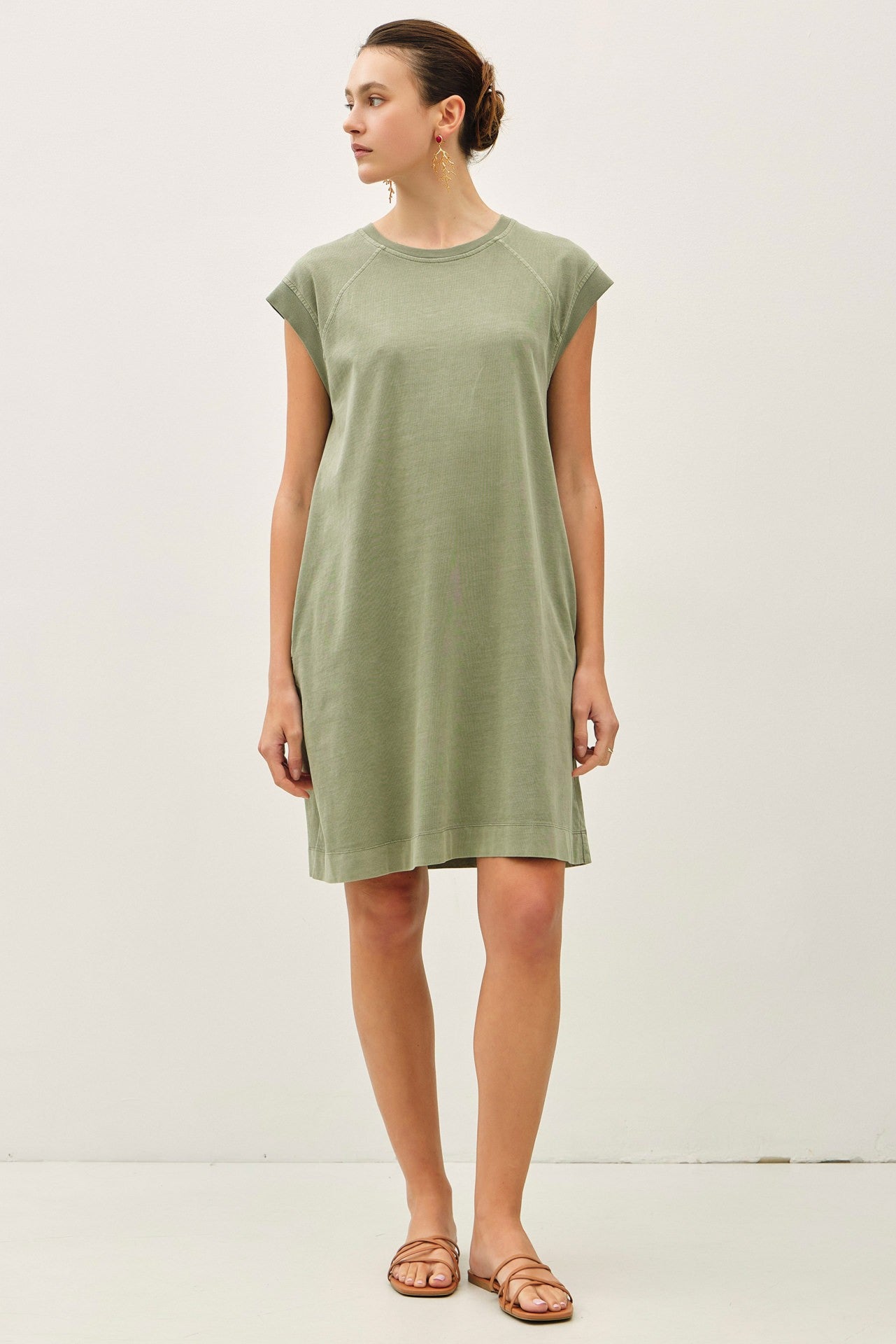 woman wearing a relaxed fit olive green cap sleeve dress with a round neckline and side pockets