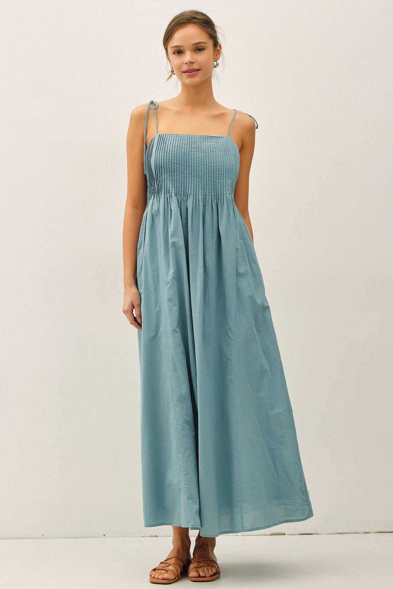 woman wearing a light blue smocked maxi dress with adjustable straps and a flowy skirt
