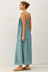 woman wearing a light blue maxi dress with tie shoulder straps and smocked bodice, shown from the back