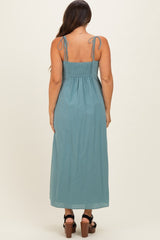 woman wearing a blue maternity maxi dress with adjustable tie straps and a smocked back design