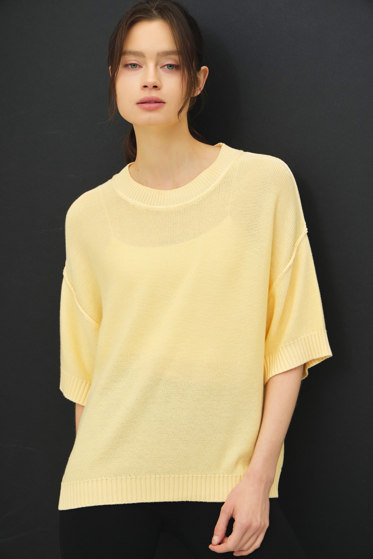 woman wearing a light yellow oversized sweater with short sleeves and a relaxed fit