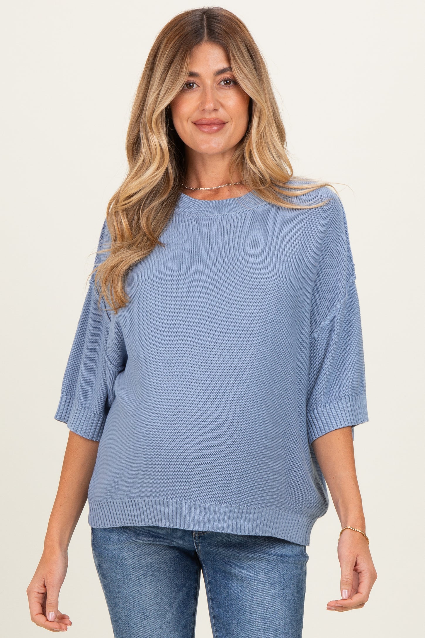 woman wearing a light blue oversized maternity sweater with half sleeves and a relaxed fit