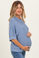 woman wearing a light blue maternity sweater and holding her baby bump