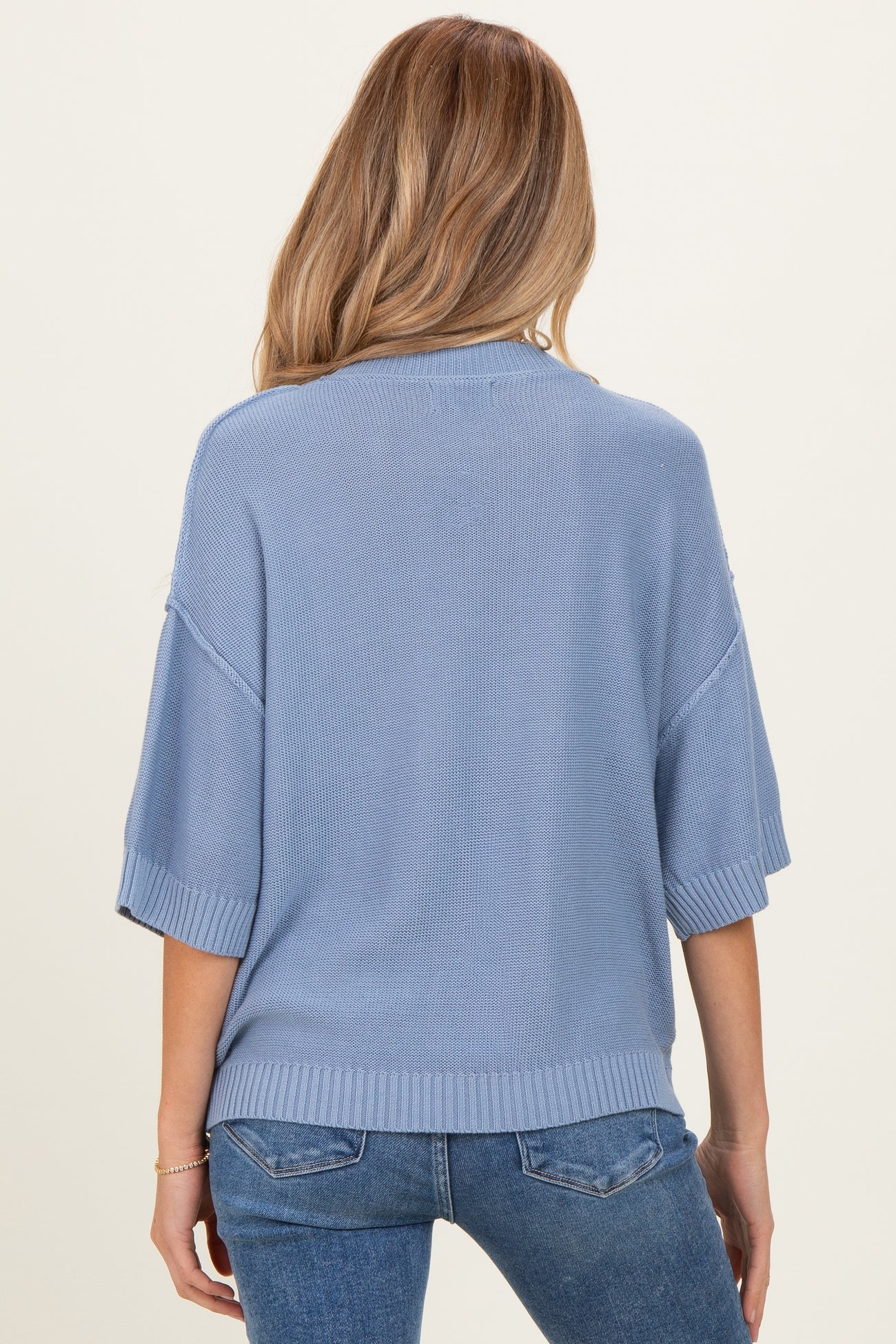 woman wearing a light blue maternity sweater with short sleeves and a relaxed fit, seen from the back