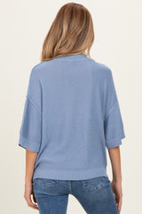 woman wearing a light blue maternity sweater with short sleeves and a relaxed fit, seen from the back