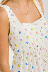 woman wearing a cream floral print sundress with square neckline and gathered waist detailing