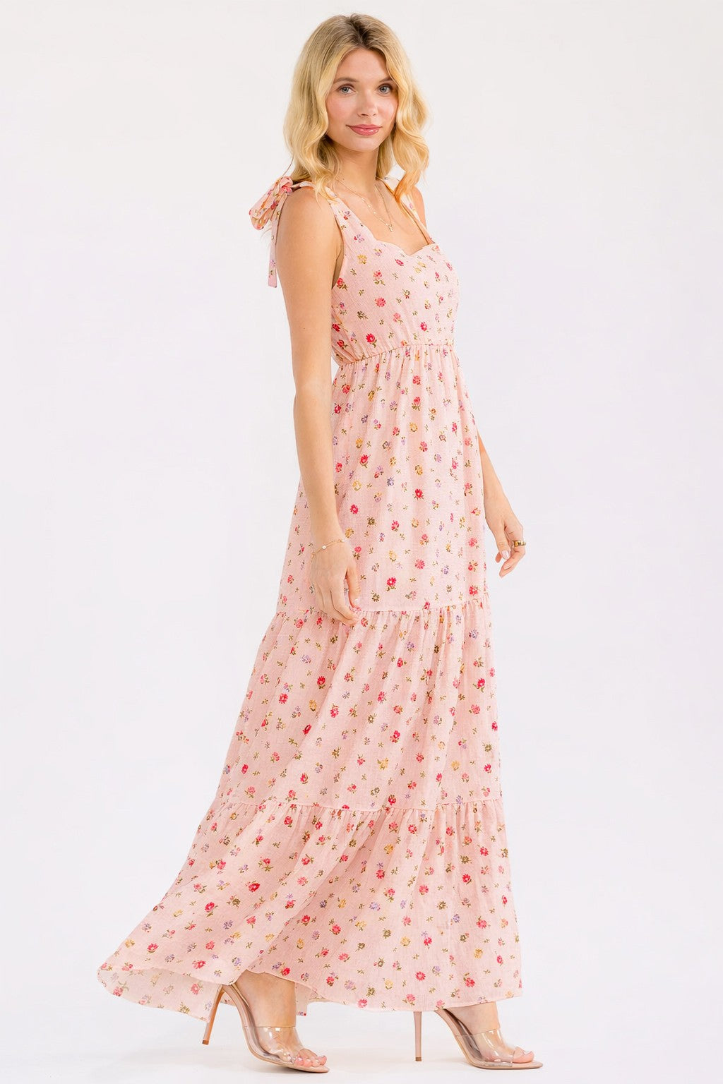 woman wearing a light pink floral maxi dress with tie straps and a tiered skirt