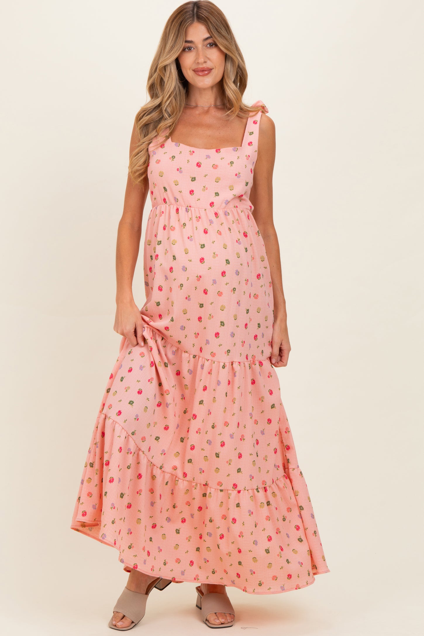 woman wearing a pink floral maternity maxi dress with tiered ruffles and a visible baby bump
