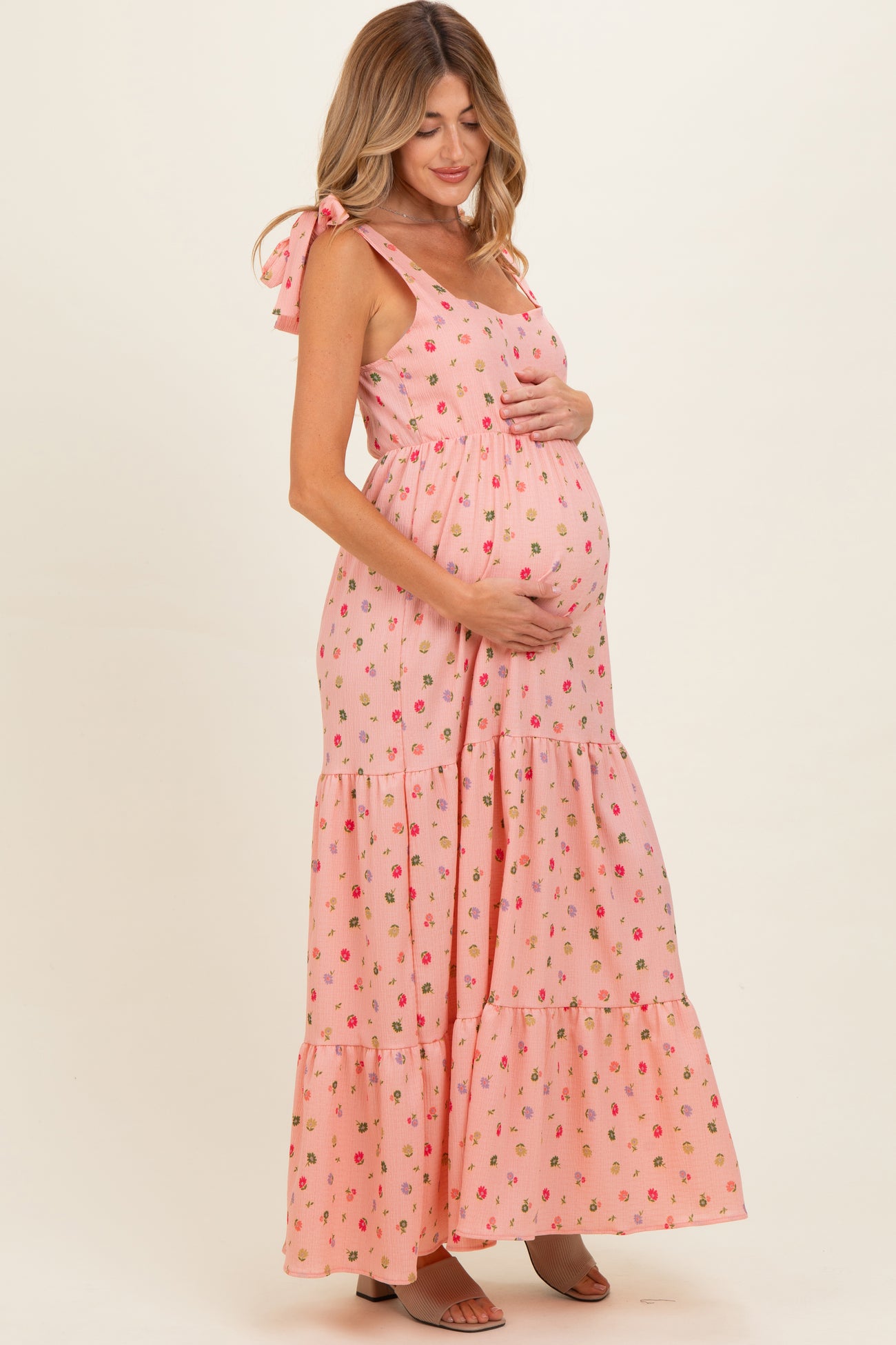 woman wearing a pink floral maternity maxi dress with tie straps and a visible baby bump