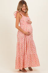 woman wearing a pink floral maternity maxi dress with tie straps and a visible baby bump