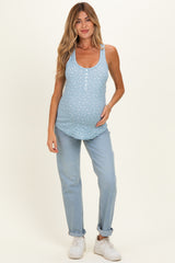 woman wearing a light blue maternity tank top with white floral print and a visible baby bump, paired with light blue jeans