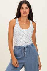 woman wearing a white tank top with blue floral print and buttons, paired with light blue drawstring pants