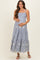 woman wearing a striped blue and white maternity maxi dress with floral details and holding her baby bump