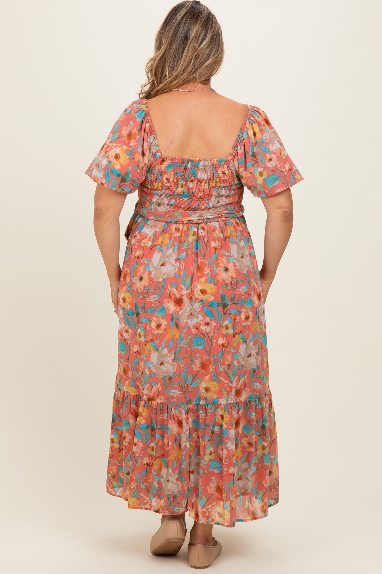 woman wearing a floral printed maternity plus maxi dress with a smocked bodice and flutter sleeves, viewed from the back