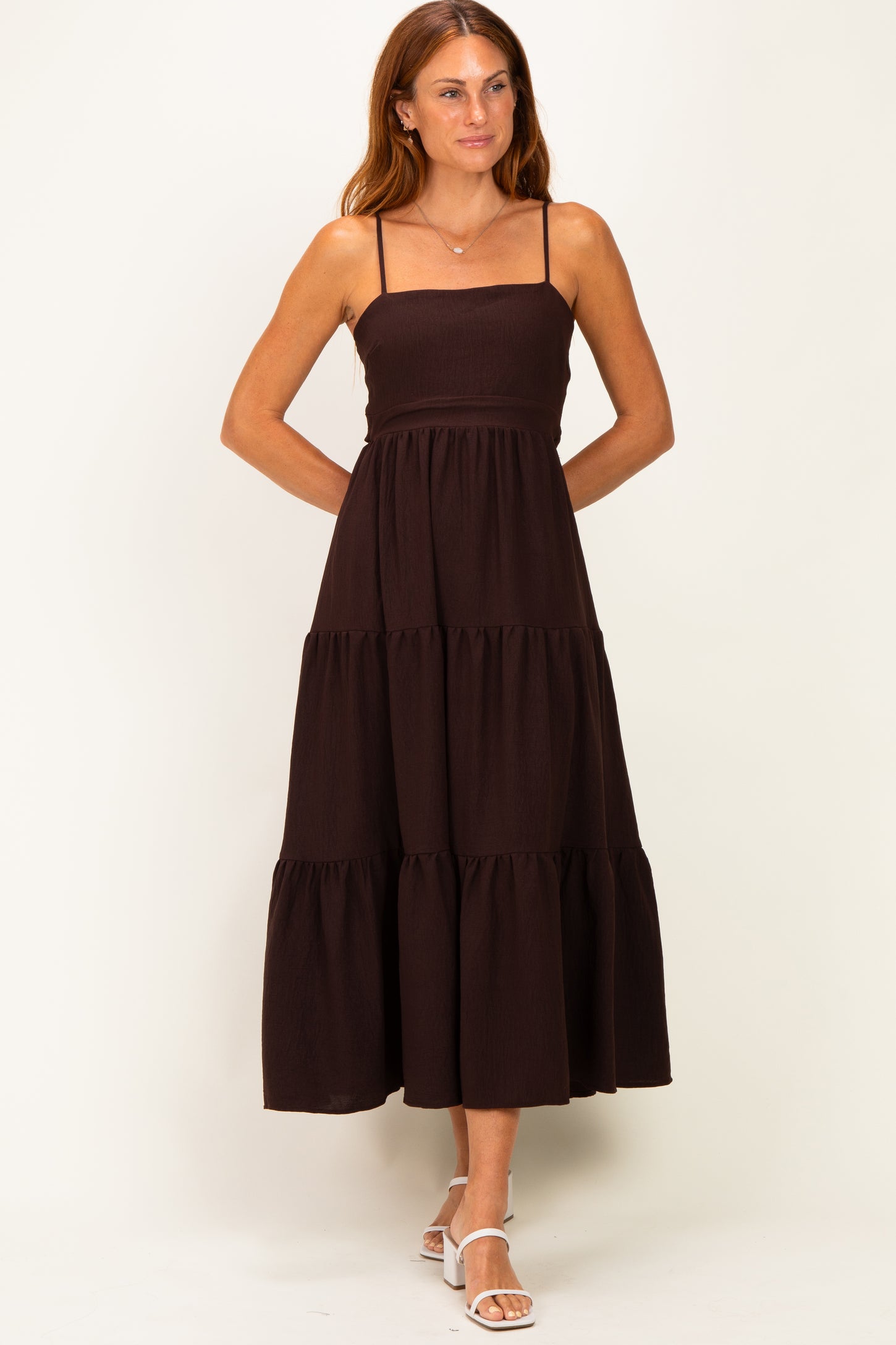 woman wearing a dark brown tiered maxi dress with spaghetti straps and a fitted bodice