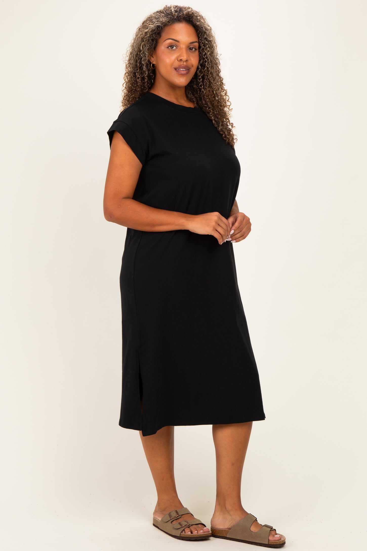 woman wearing a black short sleeve plus size dress with side slits and standing in a relaxed pose